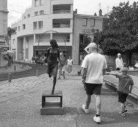 Un homme regarde une statue de femme aux seins nus.