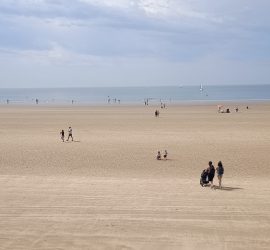 Panorama d'une page à marée basse. Les vacanciers se dirigent vers l'océan.