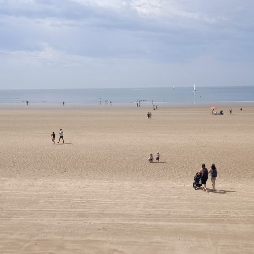 Panorama d'une page à marée basse. Les vacanciers se dirigent vers l'océan.